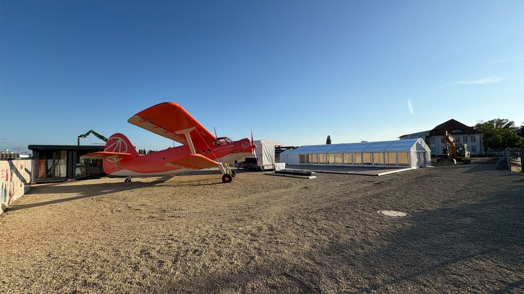 transiträume_ Bauwert Segelfliegerdamm Johannisthal; ein historisches, rotes Flugzeug auf einer Freifläche